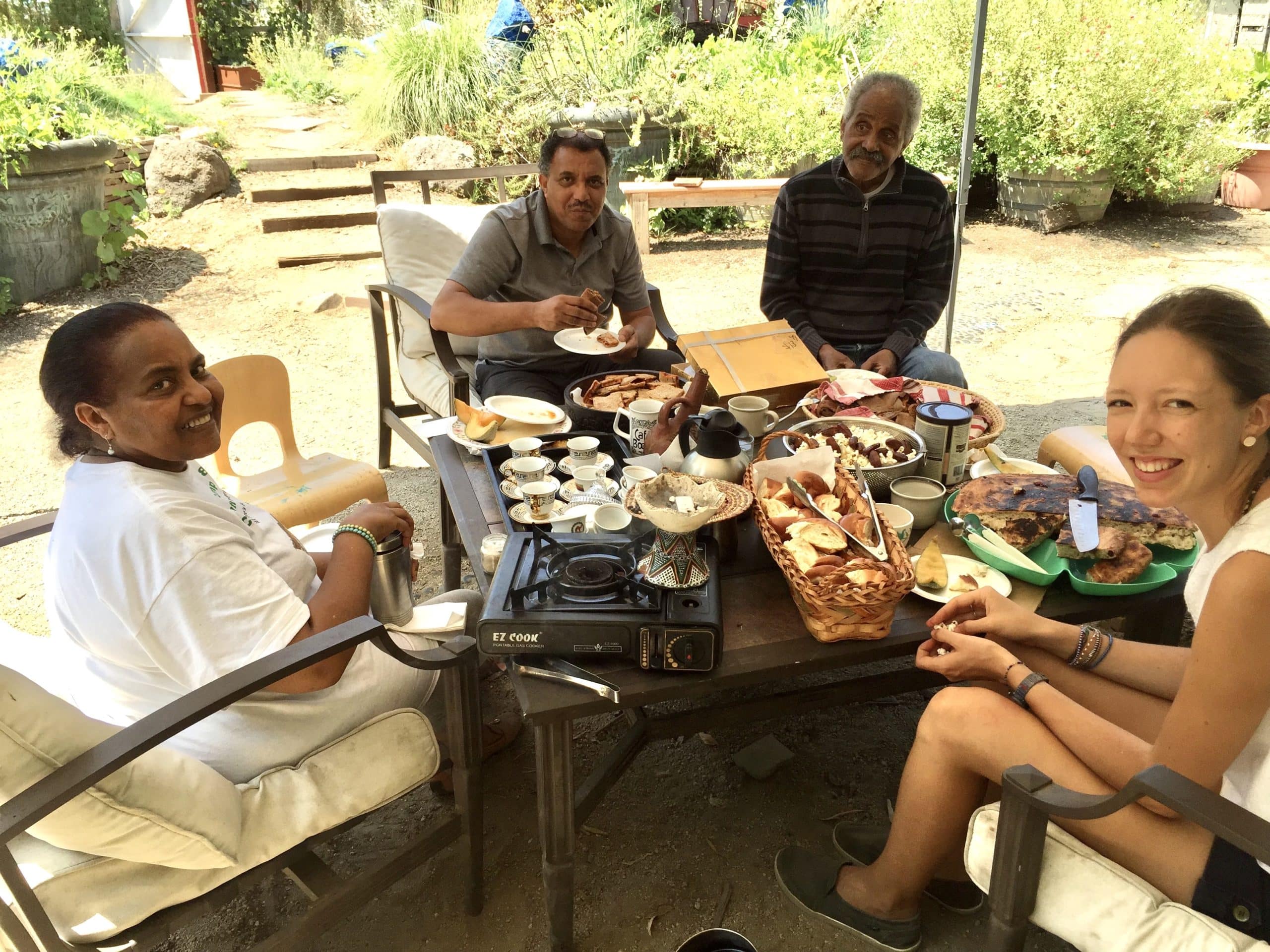 Youth Corps member eating with Eritrean members of our Mindful Aging Project (MAP). Members are serving at a traditional Eritrean coffee ceremony. Coffee is native to cloud forests in Eritrea and Kenya.